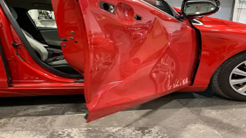 Red car with a badly dented and creased front door before crash repair, Dublin